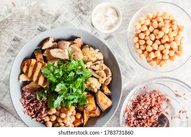 Buddha Bowl Lunch With Chicken And Red Rice, Chickpea, Cauliflower And Halloumi Cheese. Healthy Food Concept