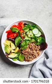 Buddha bowl salad with buckwheat, vegetables and seeds in a white plate.