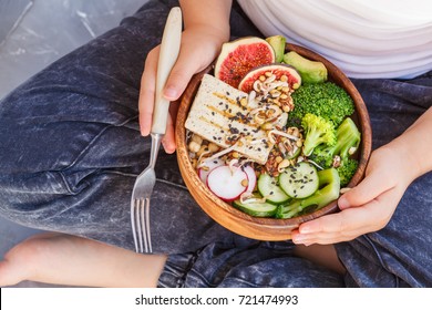 Buddha Bowl With Tofu, Broccoli And Vegetables In The Hands Of A Child. Vegan Healthy Child Food Concept.