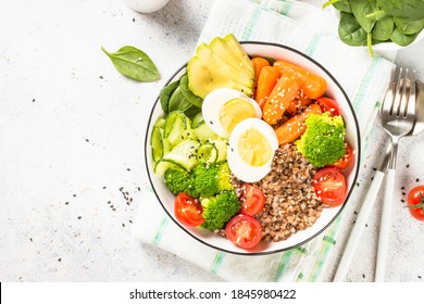 Buddha Bowl. Vegan Dish With Buckwheat, Egg, Avocado And Fresh Vegetables. Top View At Kwhite Itchen Table. Healthy Eating, Diet Menu.