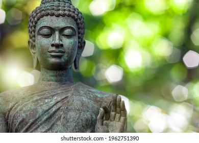 Buddha Face, The Buddha Statue Is Made Of Gold, Bronze. On Natural Bokeh Background