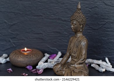 Buddha Figure With A Candle In Front Of A Dark Background.