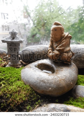 A Buddha figure and a Japanese lantern. The miniature sculpture (the property of the author of the photo) looks like a natural stone. Stylization of a Japanese garden on the windowsill.