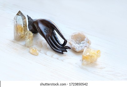 Buddha hand, quartz minerals for relaxation and meditation on white wooden background. Buddha Mudra Hand, harmony, esoteric life balance symbol. Magic crystal ritual, healing spiritual practice