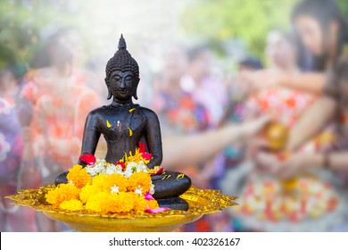 Buddha Statue Wet Water With Flower On Songkran  Festival People Blur Background In Thailand