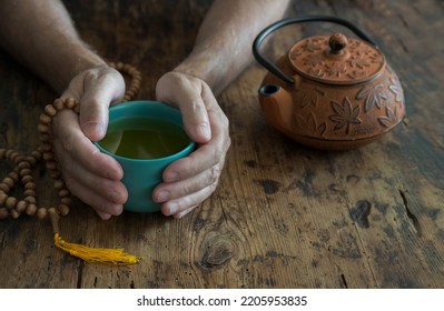 Buddhist man hands with cup of tea and teapot - Shutterstock ID 2205953835