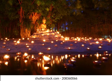 Buddhist monk fire candles to the Buddha with beautiful water reflection in Phan Tao Temple, Chiangmai, Thailand 