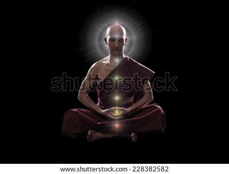 buddhist monk in meditation  pose with colorful Chakras over black background
