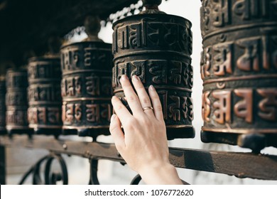 Buddhist prayer drums with close-up mantras.The female hand touches the Buddhist prayer drum, Nepal.The interaction of human energy and the Buddhist prayer drum.the girl turns the prayer drum.