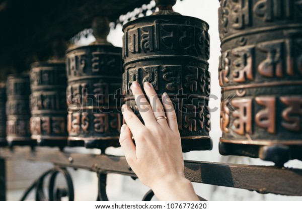 Buddhist prayer drums with close-up mantras.The\
female hand touches the Buddhist prayer drum, Nepal.The interaction\
of human energy and the Buddhist prayer drum.the girl turns the\
prayer drum.