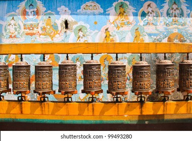 Buddhist prayer wheels with ancient art wall, Nepal