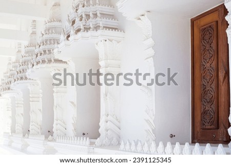 Buddhist white temple Wat Sawang Arom with convex stucco and wooden door.