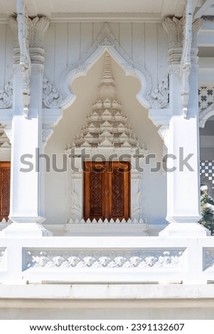 Buddhist white temple Wat Sawang Arom with convex stucco and wooden door.
