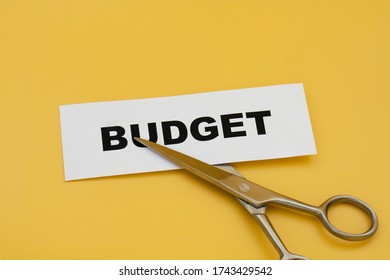 Budget Cut Concept. Scissors Cutting Paper Written Budget On Yellow Background