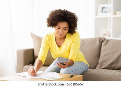 Budget, Finances And People Concept - African American Woman With Papers And Calculator Counting Money At Home