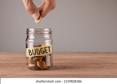 Budget. Glass jar with coins and an inscription budget. Man holds  coin in his hand - Shutterstock ID 1159828186