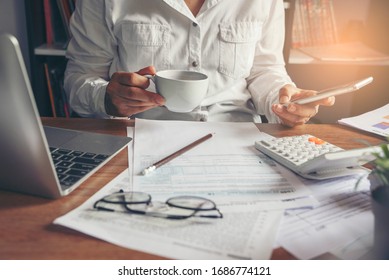 Budget planning concept. Accountant using smartphone calculating return tax. Calendar 2021 and personal income annual tax forms for those who have income under US law placed on office desk.