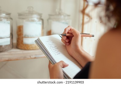 Budget planning, making shopping list and managing household expenses to save money. Financial accountability at home. Woman making shopping list for groceries on a notebook to plan a meal for