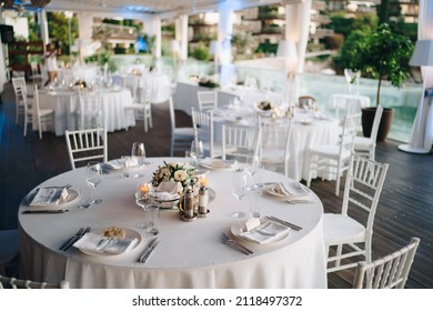 Budva, Montenegro - 14.07.21: Wedding dinner table reception. Round banquet table with white tablecloth and white Chiavari chairs. Wedding under the tent. 