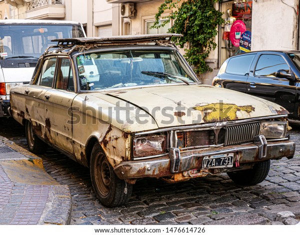 Buenos\
Aires / Argentina - December 2017: Derelict abandoned car in the\
street of Buenos Aires. Rusty damaged\
vehicle.