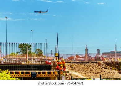 BUENOS AIRES, ARGENTINA - NOVEMBER 23, 2017: Masons Work On A Construction Site On The Concrete Framework While An Airplane Passes From Behind