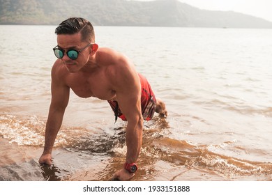 A Buff Asian Man Wearing Shades Does Pushups At The Beach. Chest Workout Or Calisthenics Outdoors.