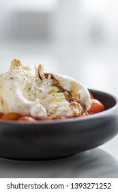 Buffalo Burrata Mozzarella Cheese Ball With Cocktail Tomatoes, Olive Oil And Balsamic Vinegar On Black Plate