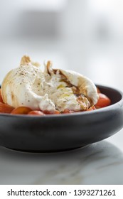 Buffalo Burrata Mozzarella Cheese Ball With Cocktail Tomatoes, Olive Oil And Balsamic Vinegar On Black Plate