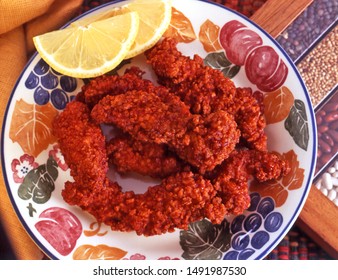 Buffalo Chicken Tenders On Patterned Plate With Lemon Wedge.