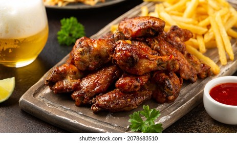 Buffalo chicken wings with beer, french fries on wooden board. fast food