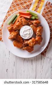 Buffalo Chicken Wings With Cheese Sauce And Celery On The Table Close-up. Vertical Top View
