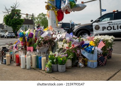 Buffalo, New York-May 21, 2022:  Memorial with flowers and candles to honor the victims of the mass shooting at the Tops market in Buffalo NY. A police SUV is turning the corner in the background