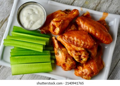 Buffalo Wings With Celery And Ranch Dressing On A White Plate