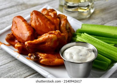 Buffalo Wings With Celery Sticks And Ranch Dressing On A White Plate