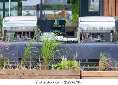 Buffet Heated Trays Standing In Line Ready For Service. Outdoors Buffet Restaurant, The Hotel Restaurant. Warming Trays For Buffet Line On The Table Outdoors