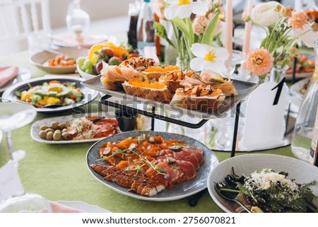Buffet table set for brunch with beautiful floral decorations, antipasti, bruschetta, and smoked salmon creating an inviting spread