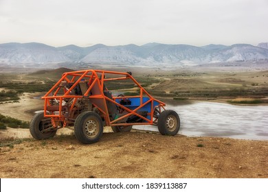 Buggy sports car On the mountain in front of the lake against the background of mountains on a clear day