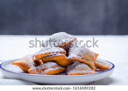 Bugie or ravioli filled with chocolate cream, traditional italian carnival fritters on white plate.
