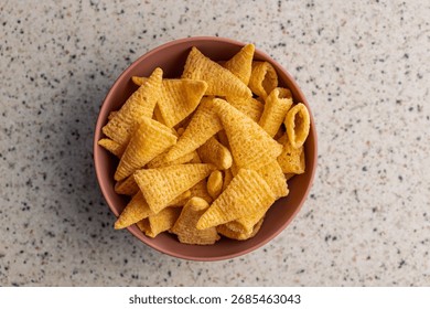 Bugles snack. Cone corn chips in bowl on a kitchen table. Top view.