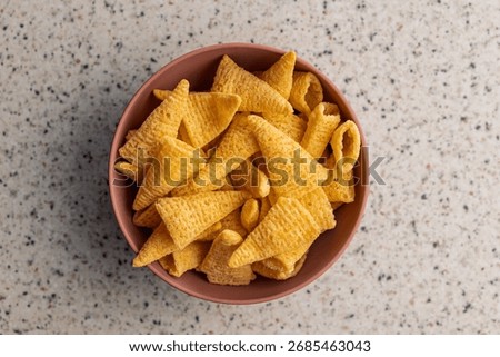 Bugles snack. Cone corn chips in bowl on a kitchen table. Top view.