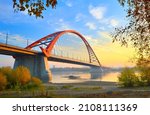 Bugrinsky bridge in golden autumn. Arched automobile bridge on the banks of the Ob River among the crowns of trees. Novosibirsk, Siberia, Russia, 2021