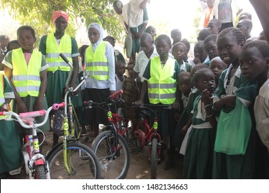 Buiba, Gambia, Africa, May 6, 2019: Horizontal Photography Of A Group Of Elementary School Students With New Bikes And Travel Vests, Outdoors On A Sunny Day