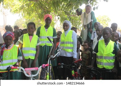 Buiba, Gambia, Africa, May 6, 2019: Horizontal Photography Of A Group Of Elementary School Students With New Bikes And Travel Vests, Outdoors On A Sunny Day