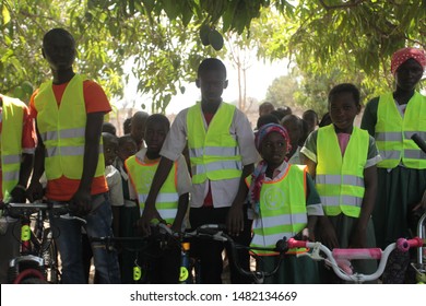 Buiba, Gambia, Africa, May 6, 2019: Horizontal Photography Of A Group Of Elementary School Students With New Bikes And Travel Vests, Outdoors On A Sunny Day