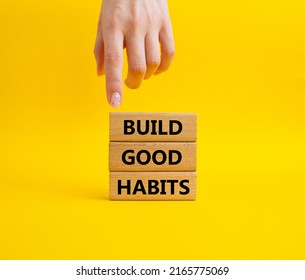 Build good habits symbol. Wooden blocks with words 'Build good habits'. Beautiful yellow background. Businessman hand. Business and 'Build good habits' concept. Copy space