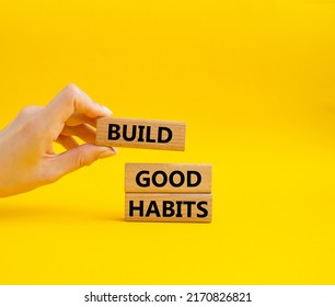Build good habits symbol. Wooden blocks with words 'Build good habits'. Beautiful yellow background. Businessman hand. Business and 'Build good habits' concept. Copy space. . Conceptual image