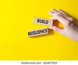 Build resilience symbol. Wooden blocks with words Build resilience. Beautiful yellow background. Businessman hand. Business and Build resilience concept. Copy space. - Shutterstock ID 2224877819