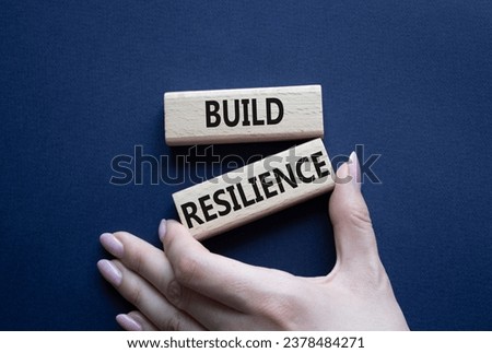 Build resilience symbol. Wooden blocks with words Build resilience. Beautiful deep blue background. Businessman hand. Business and Build resilience concept. Copy space.