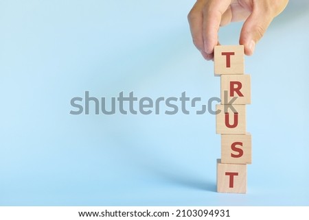 Build trust concept. Hand stacking wooden blocks with word trust.