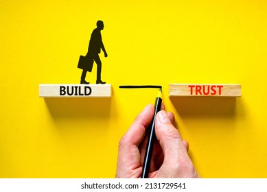 Build trust symbol. Concept words Build trust on wooden blocks on a beautiful yellow table yellow background. Businessman hand. Business and build trust concept, copy space.